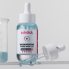 Eine blaue Flüssigserumflasche mit der Aufschrift "Skinlick Neuropeptide Pure Shot 5%" mit einer Pipette und einem Glasbecher im Hintergrund.