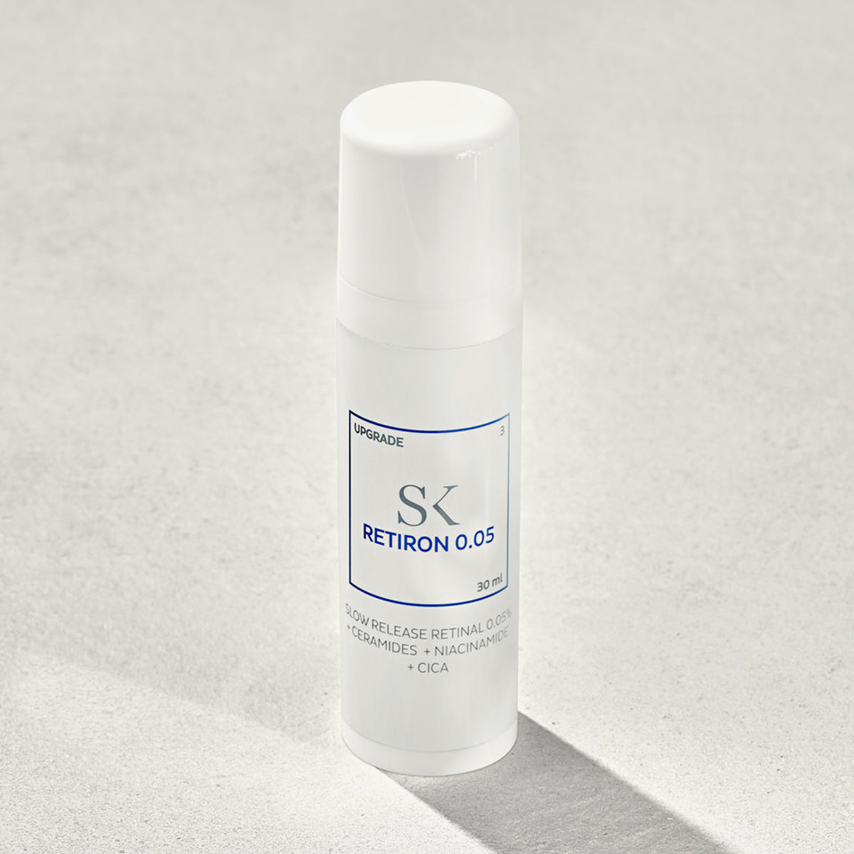 Weiße Flasche des Hautpflegeprodukts Retiron 0,05 auf einer hellgrauen Oberfläche.