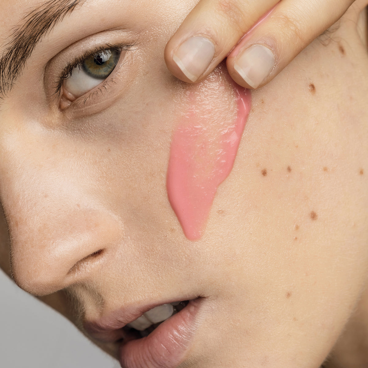 Nahaufnahme des Gesichts einer Frau, auf deren Wange Spectra-Rosa-Gel aufgetragen wird.