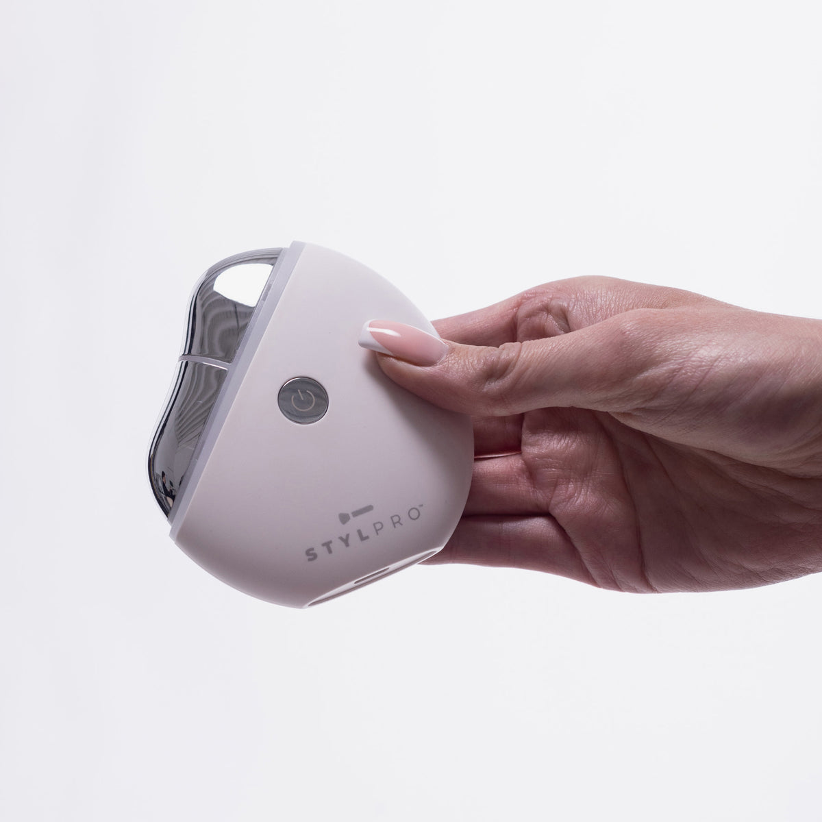 Eine Hand hält ein kleines, weißes STYLPRO Gua Sha-Gerät mit einer Einschalttaste und einem schlanken, geschwungenen Design.