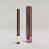 Ein brauner Cupid's Arrow Longwear Stylo Eyeliner-Stift steht neben der passenden Schachtel auf einem hellgrauen Hintergrund.