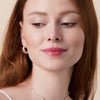 Eine Frau mit roten Haaren und heller Haut präsentiert das Glossin‘ Glow Tinted Lip Oil 030.