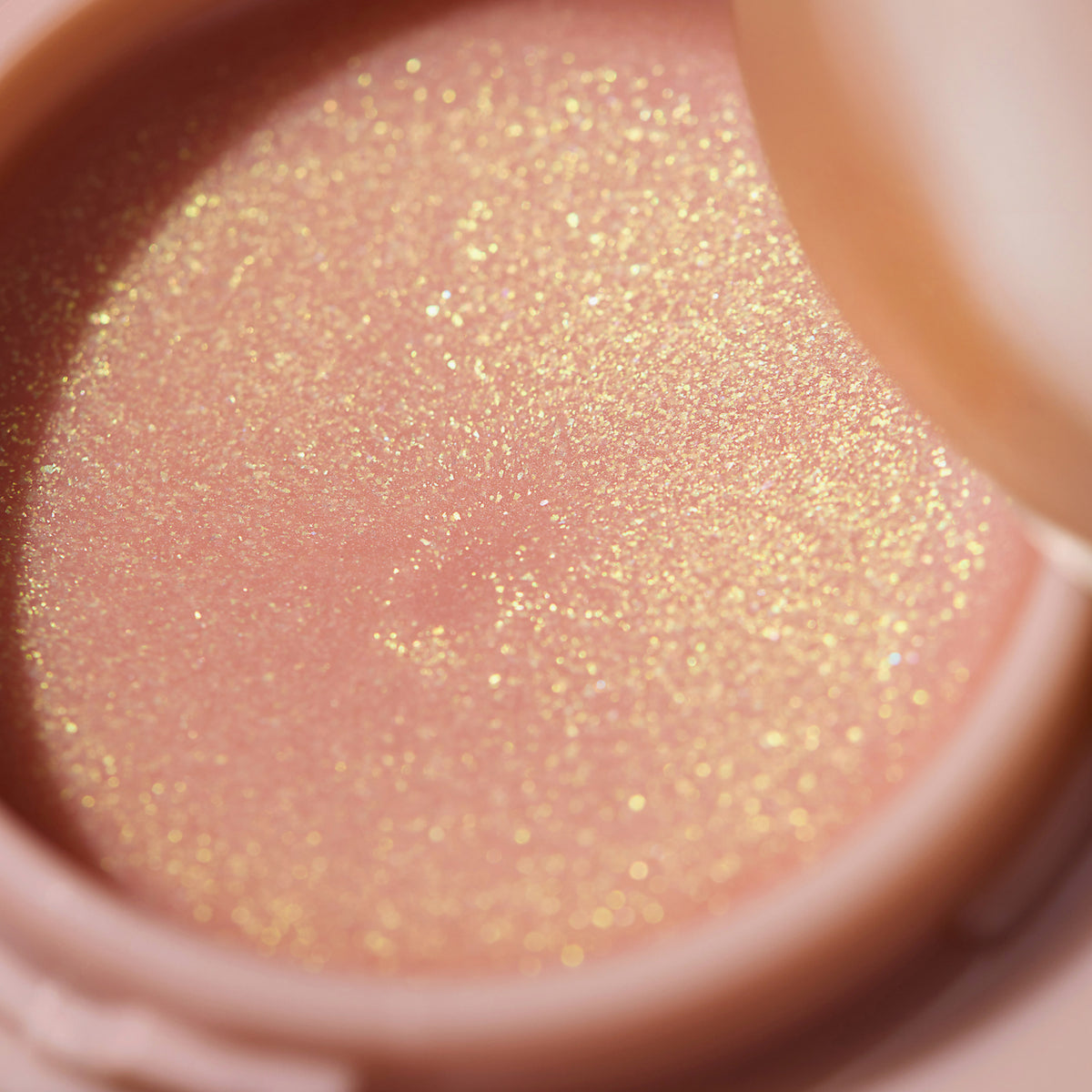 Nahaufnahme des gold-schimmernden pfirsichfarbenen KISS & GLOW Shimmer Lip Balm C01 angestrahlt von der Sonne.