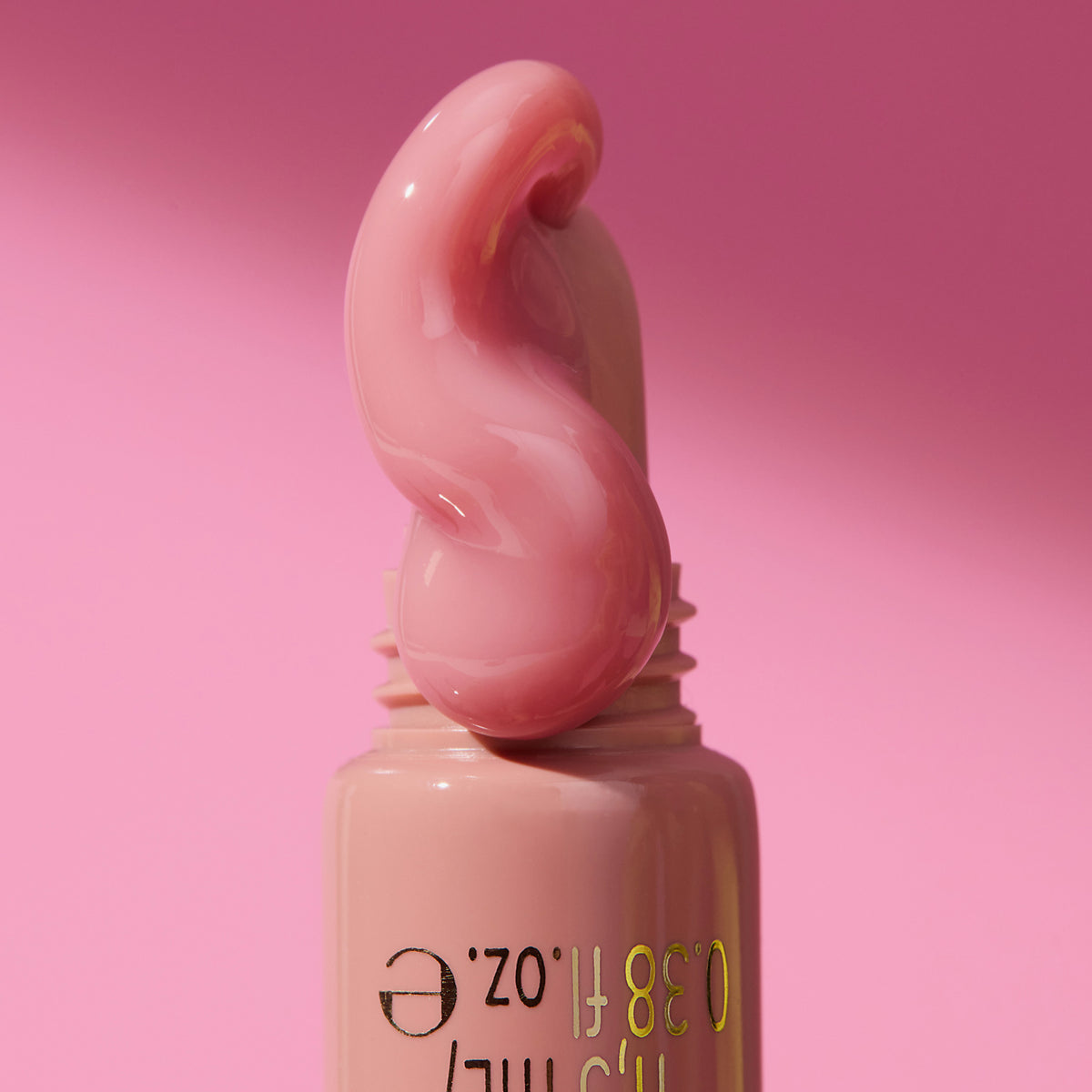 Nahaufnahme des KISS & GLOW Peptide Lip Tint Applikators mit einem Wirbel aus nude-rosa Gloss, vor rosa Hintergrund.