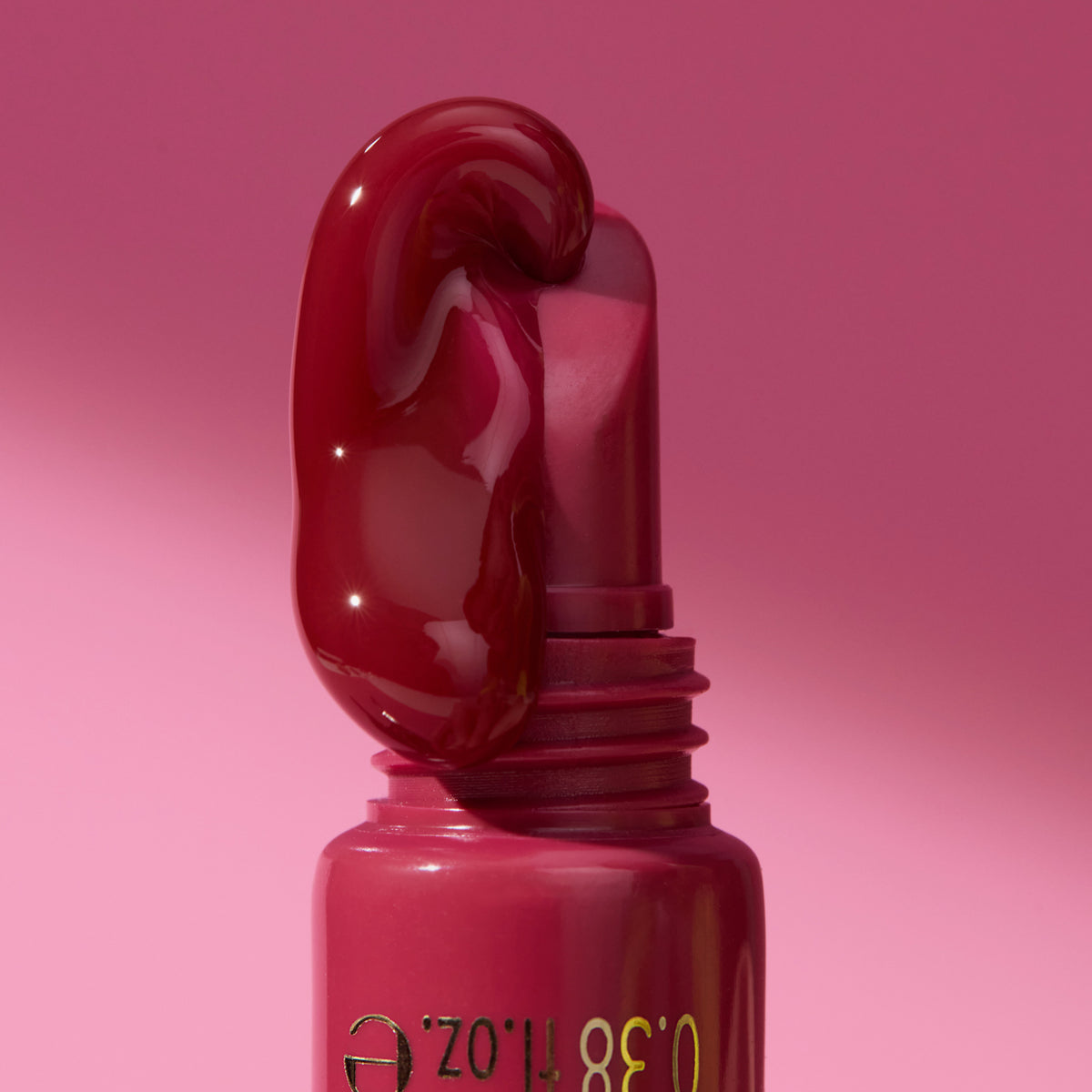 Nahaufnahme des KISS & GLOW Peptide Lip Tint C03 in Rot, wobei der Gloss aus dem Applikator herunterfließt; vor pinkem Hintergrund.