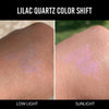 Eine Hand zeigt Farbmuster des Infinite Chrome Pencil Lilac Quartz bei schwachem Licht (violett schimmernd) und im Sonnenlicht (rosa-violett schimmernd).