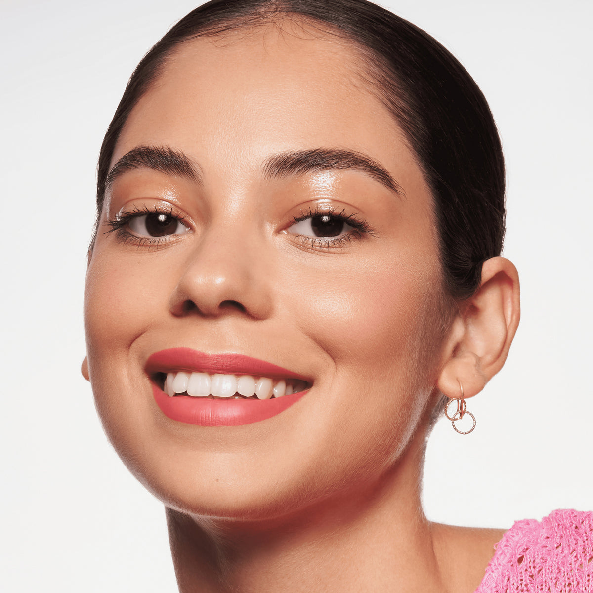 Person mit mittlerem Teint und dunklen Haaren lächelt und präsentiert den BABY GOT GLOW liquid highlighter 10 auf den Wangen.