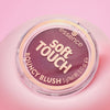 Ein runder Behälter von Essence soft TOUCH BOUNCY BLUSH ist vor einem rosa Hintergrund abgebildet.