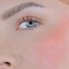 Nahaufnahme des Gesichts einer Person mit rosa Wangen geschminkt mit dem Blush Stick – 2-in-1 Creme Rouge mit Pinsel.