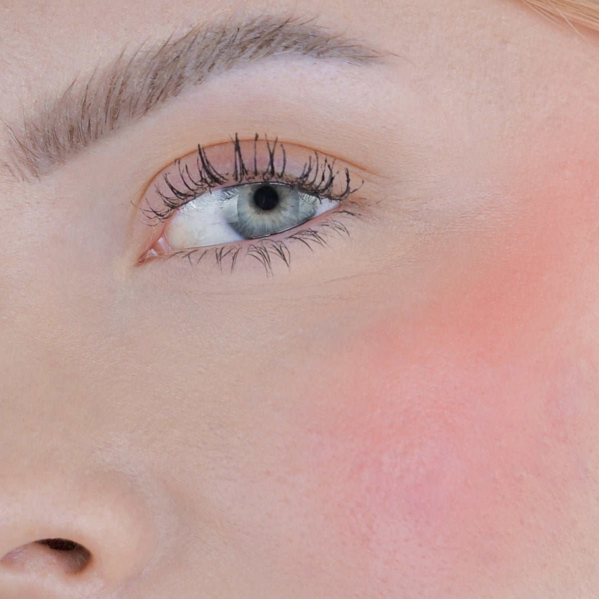 Nahaufnahme des Gesichts einer Person mit rosa Wangen geschminkt mit dem Blush Stick – 2-in-1 Creme Rouge mit Pinsel.