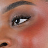 Nahaufnahme des Gesichts einer Person mit rosa Wangen geschminkt mit dem Blush Stick – 2-in-1 Creme Rouge mit Pinsel.