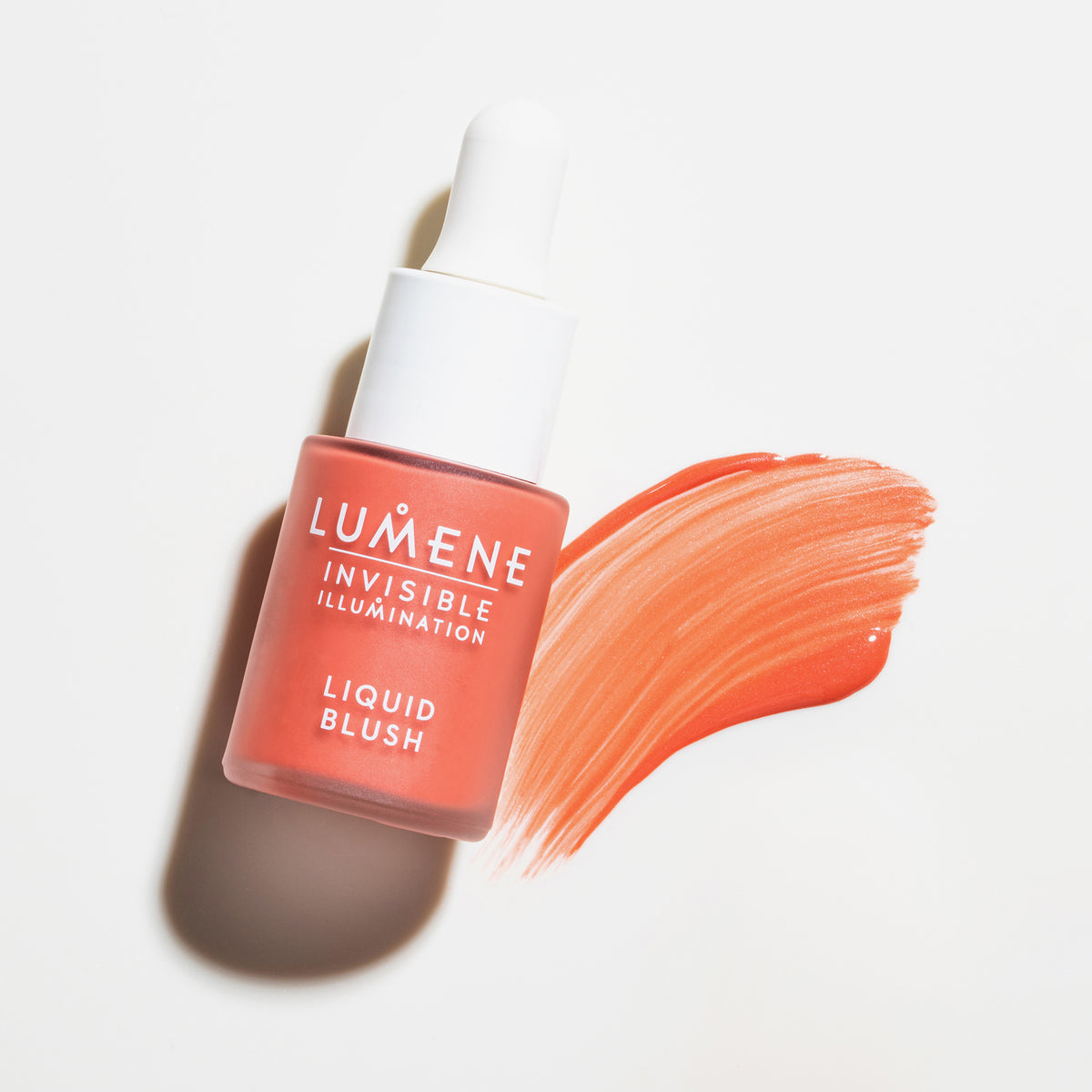 Eine Flasche Lumene INVISIBLE ILLUMINATION Liquid Blush Bright Blossom mit einem korallenroten Muster daneben auf weißem Hintergrund.