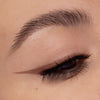 Nahaufnahme eines geschminkten Auges mit einem soften, braunen Wing-Look. Die Linie ist dezent verblendet und betont die natürliche Augenform.