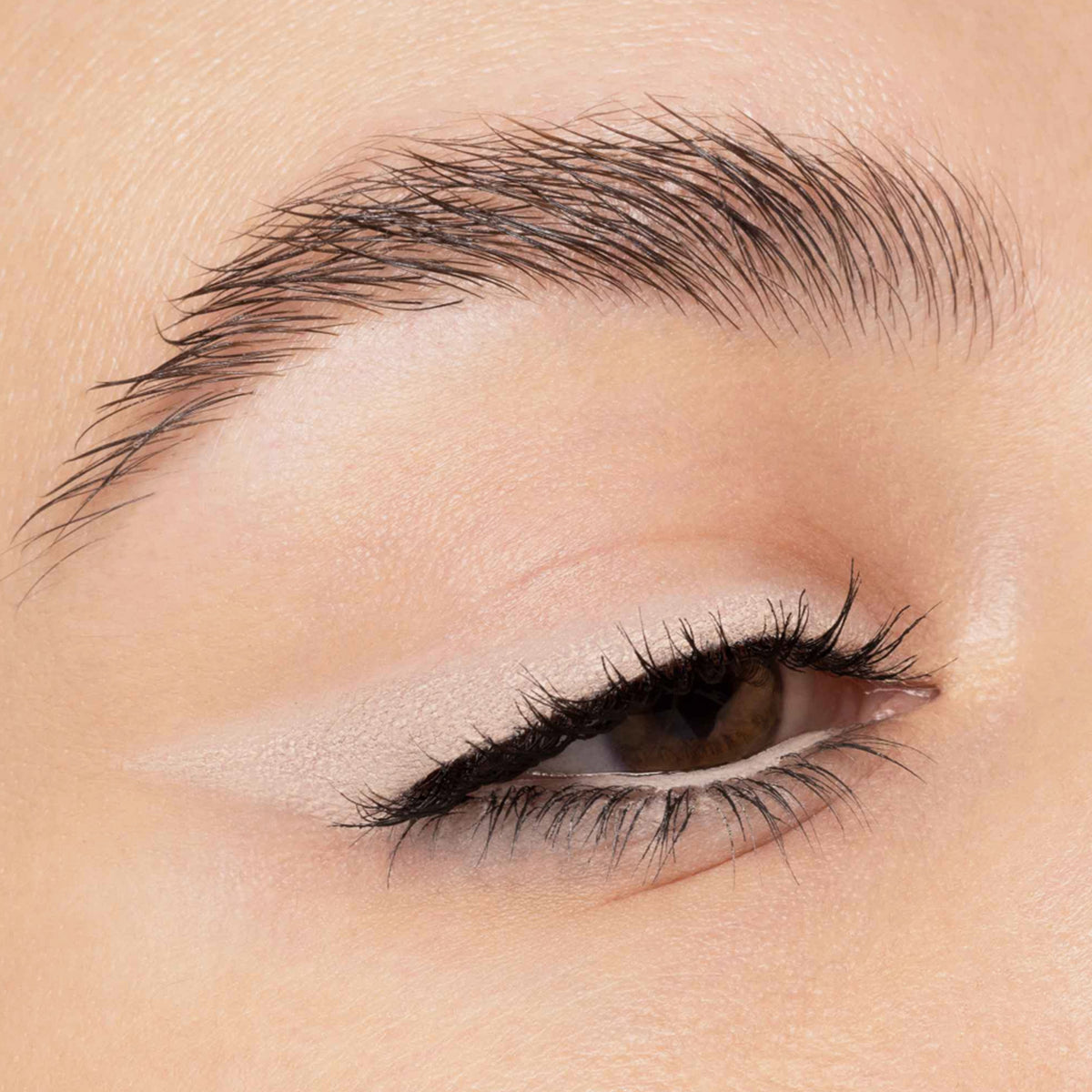 Nahaufnahme eines Auges mit beigefarbenem Lidschatten in Wing-Form und schwarzem Eyeliner auf dem oberen und unteren Wimpernkranz.