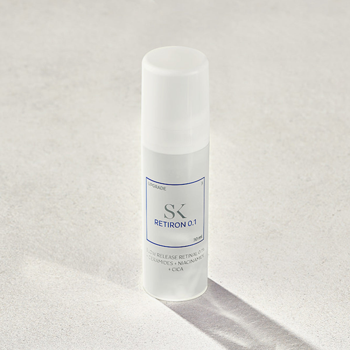 Eine weiße Flasche mit der Aufschrift „Retiron 0.1“ steht auf einem neutralen Hintergrund und wirft einen sanften Schatten.