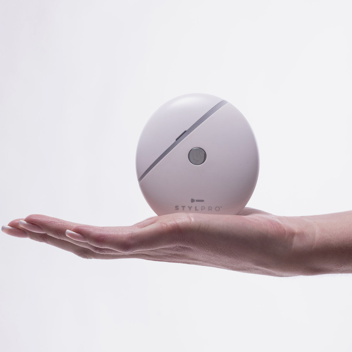 Eine Hand hält ein rundes, weißes STYLPRO Gua Sha-Gerät vor einem schlichten weißen Hintergrund.