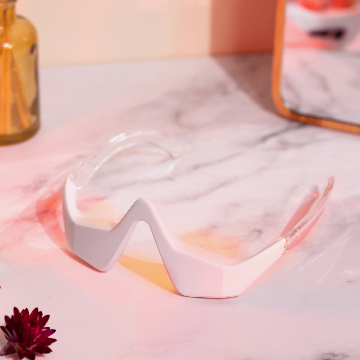 Die Brille wird auf einer Marmoroberfläche neben einem Spiegel und Dekorationsgegenständen präsentiert.