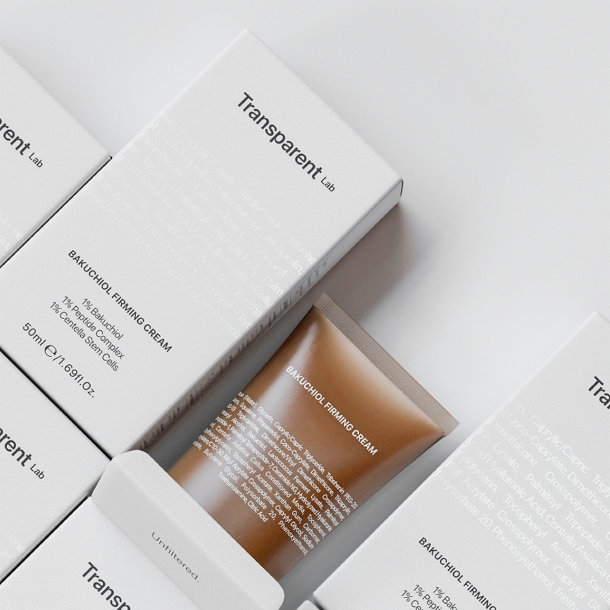 Eine Tube Bakuchiol Firming Cream in Braun liegt halb aus der Verpackung; umgeben von weiteren geschlossen Verpackungen.