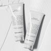 Zwei Tuben der Time Reverse Beauty Sleep Mask von Transparent Lab auf einer strukturierten weißen Oberfläche.