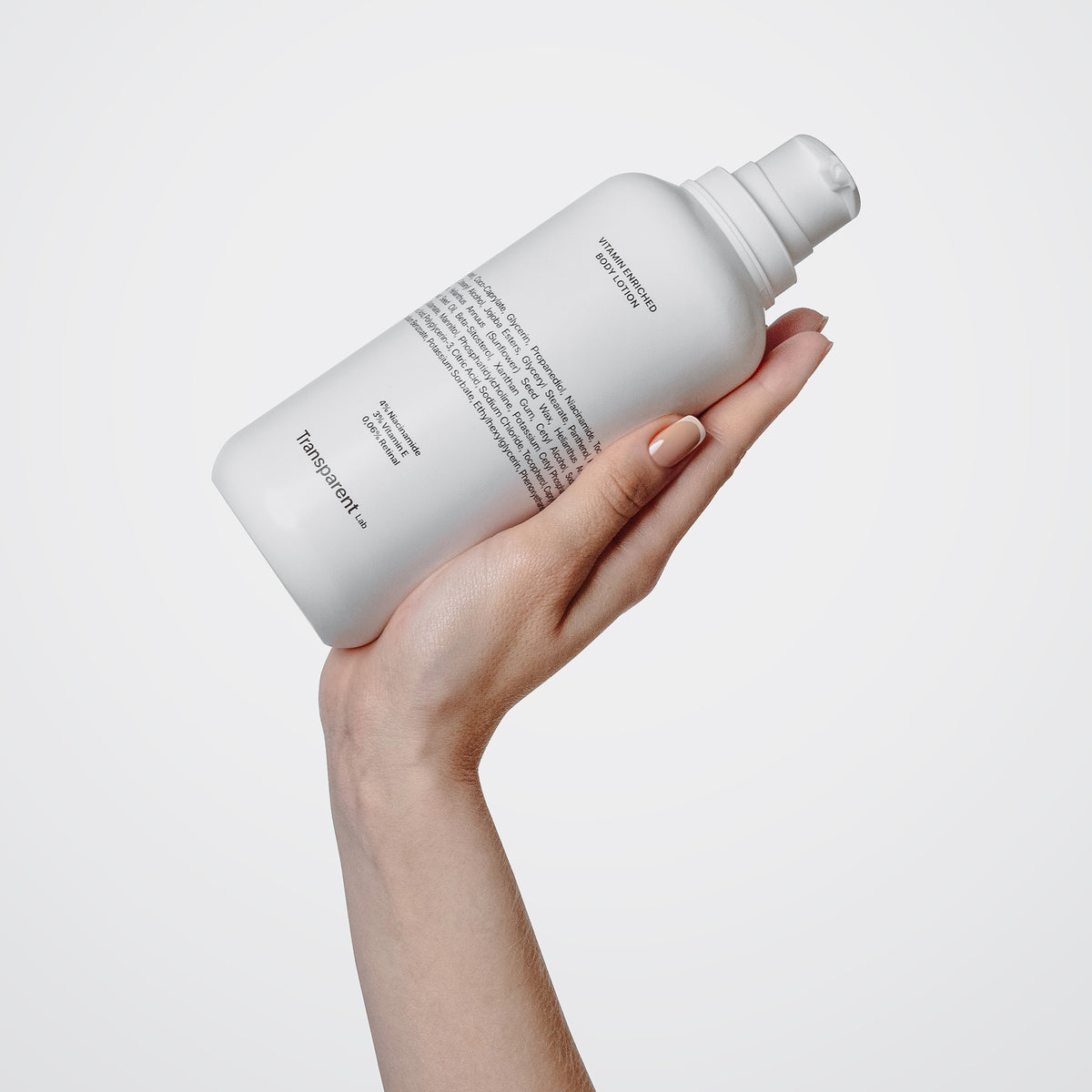 Eine Hand hält eine Flasche der Vitamin Enriched Body Lotion mit schwarzem Text auf weißem Hintergrund.