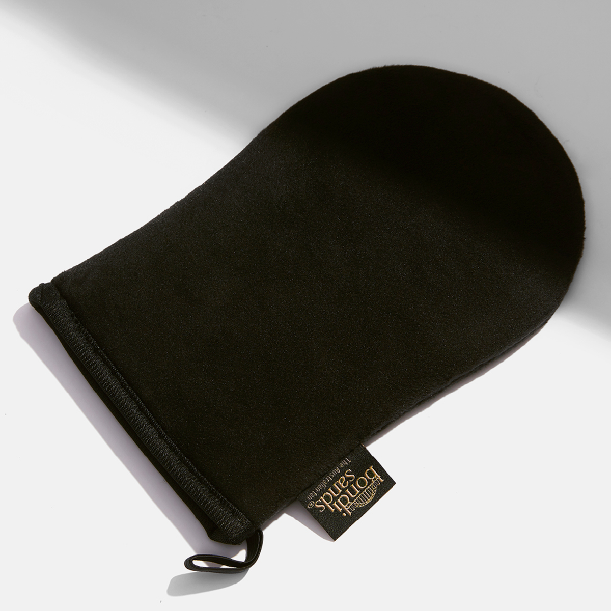 Der schwarze Bondi Sands Application Mitt auf einer weißen Oberfläche.