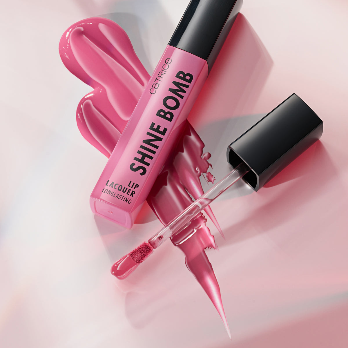 Rosafarbene Tuben Catrice Cosmetics Shine Bomb Lip Lacquer 060 mit offenem Applikator und glänzenden Farbmustern.
