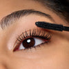 Nahaufnahme einer Person, die Catrice Cosmetics TUBING Stay In Place Volume Mascara 010 auf ihre oberen Wimpern aufträgt.