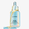 Schillernde Flasche Youth Juice Collagen Scalp Treatment mit gelbem Serum, dass über die Flasche läuft.