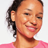 Sommersprossige Frau mit mittlerem Teint und dunklem Haar präsentiert die DROP OF sunshine BRONZING DROPS.