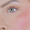 Nahaufnahme des Gesichts einer Person mit rosa Wangen geschminkt mit dem Blush Stick – 2-in-1 Creme Rouge mit Pinsel.