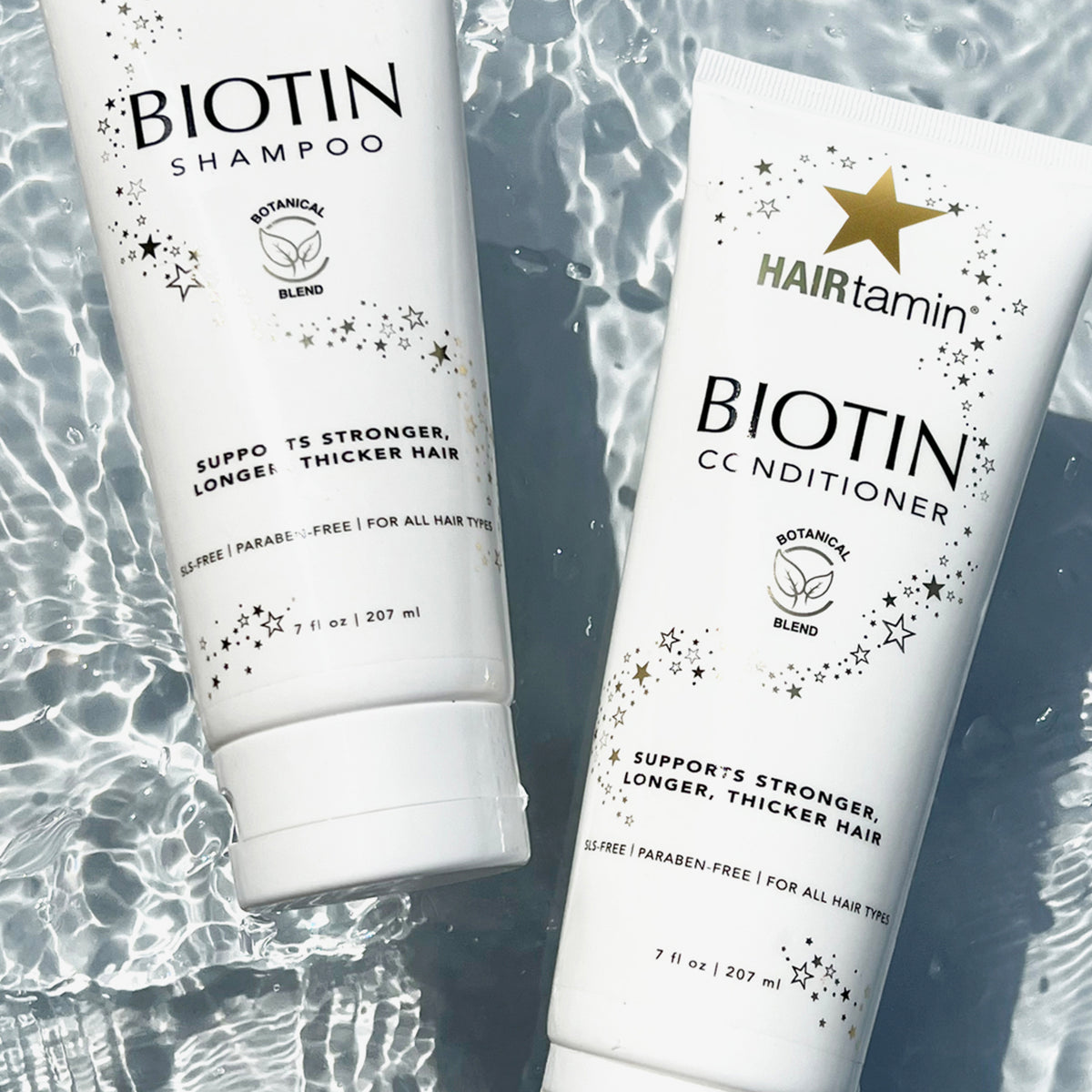 Zwei weiße Tuben Biotin Conditioner und Shampoo schwimmen in Wasser.