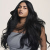 Frau mit langem, welligem, schwarzem Haar, gestylt mit dem Living Proof Perfect Hair Day 5-in-1-Styling Treatment.