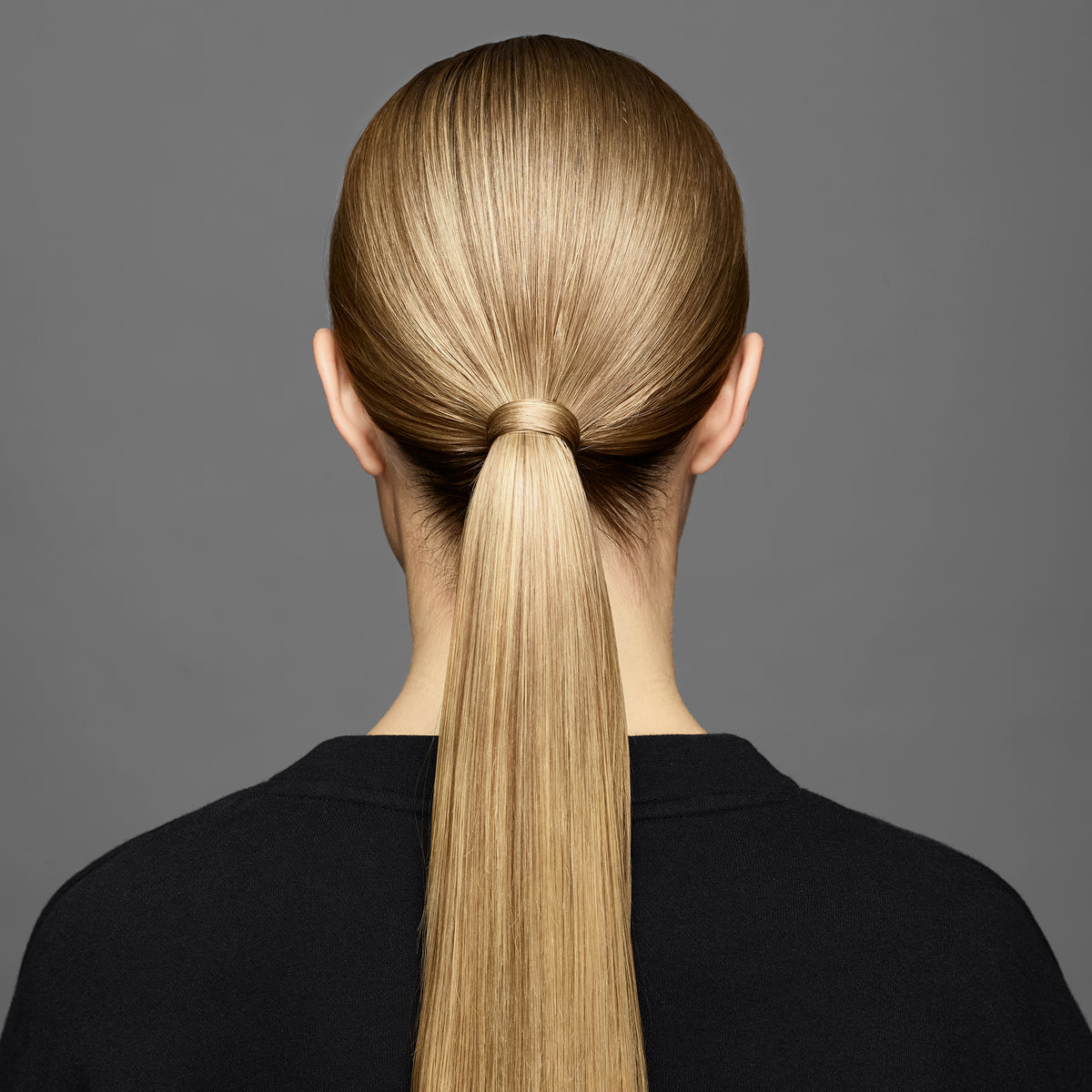 Eine Frau mit glattem blondem Haar in einem glatten niedrigen Pferdeschwanz, gestylt mit maria nila Gabbro Fixating Wax.
