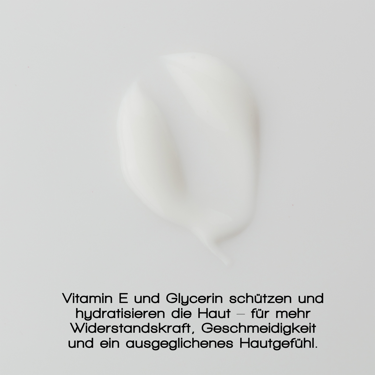Ein Abstrich der MERME Gentle Barrier Face Cream ist auf einer glatten Fläche zu sehen, darunter ein deutscher Text, der die Vorteile von Vitamin E und Glycerin hervorhebt.