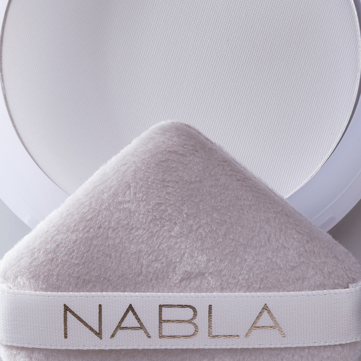 Nahaufnahme einer Puderquaste vor einer weißen Kompaktpackung Close-up Blotting Pressed Powder.