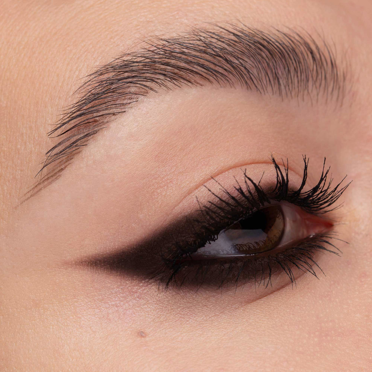 Nahaufnahme eines Auges mit soft verblendetem dunkelbraunem Lidschatten, der in einem smokey Wing ausläuft. Der Look betont den äußeren Augenwinkel.