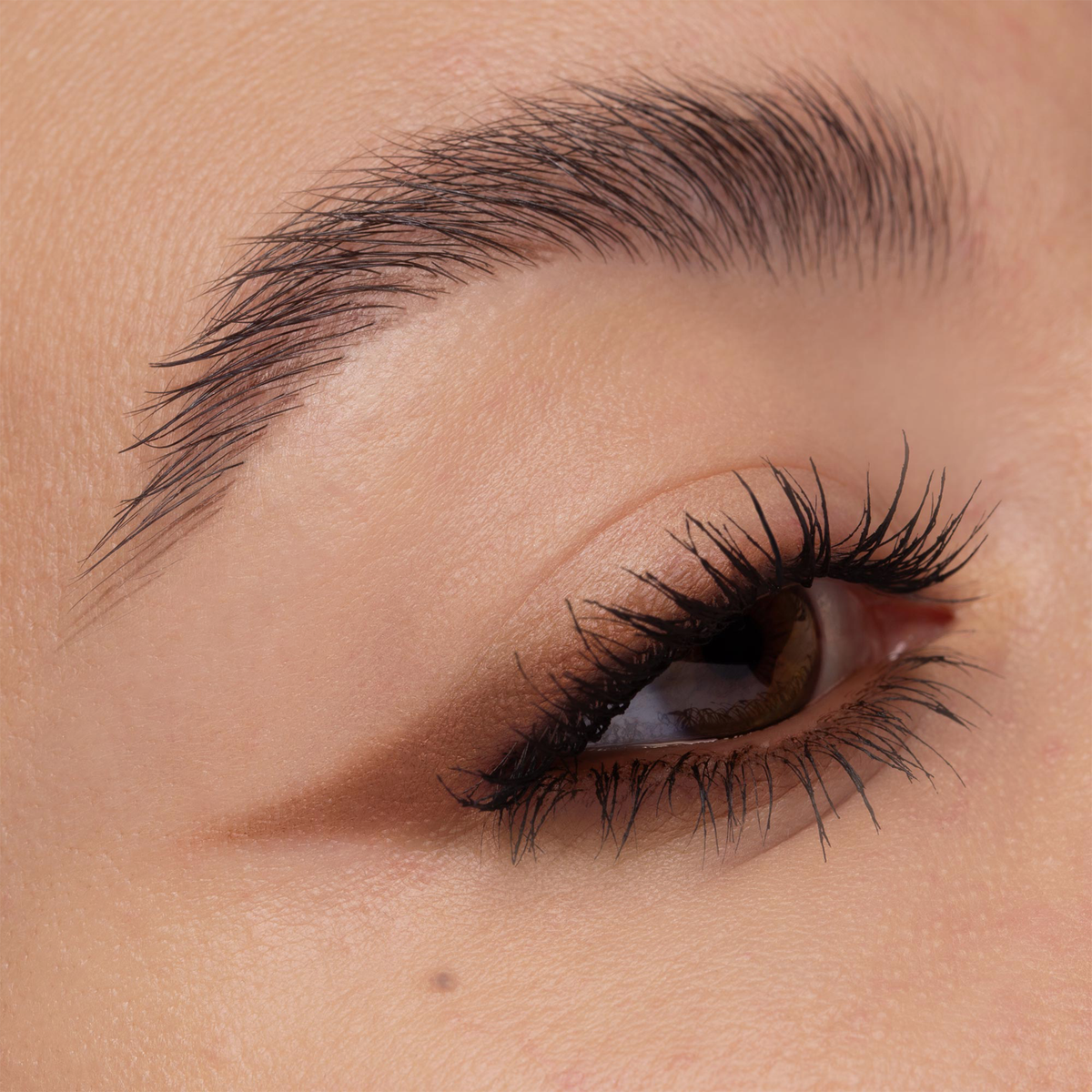 Nahaufnahme eines Auges mit braunfarbenem Winged-Liner-Look. Der Liner verläuft spitz nach außen, die Wimpern sind definiert.