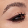 Nahaufnahme eines Auges mit kantigem, beerenfarbigem Winged-Liner-Look. Der Liner verläuft spitz nach außen, die Wimpern sind definiert.