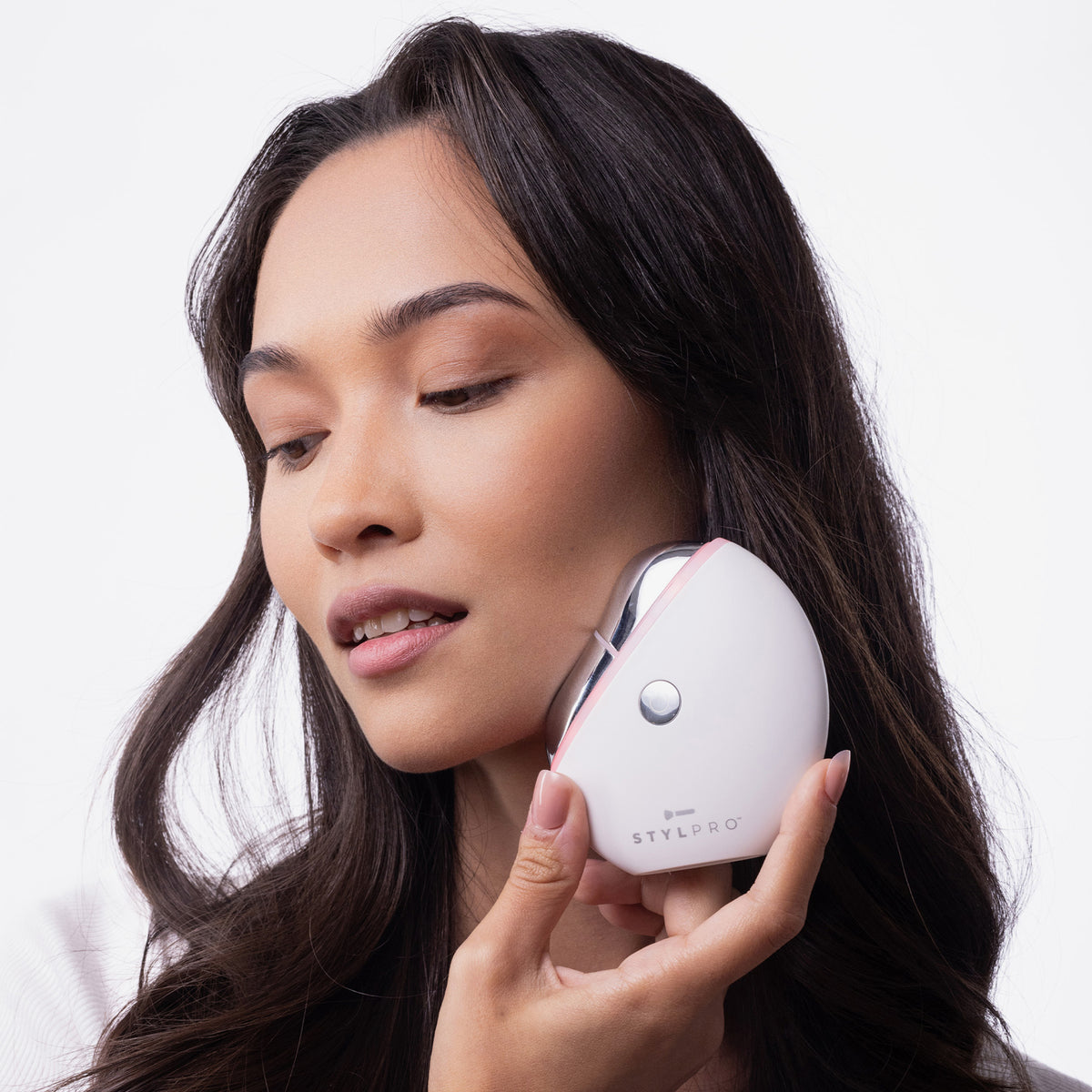 Eine Frau hält ein weißes STYLPRO Gua Sha an ihre Kieferpartie vor einem schlichten weißen Hintergrund.