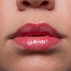 Nahaufnahme von glänzenden, rosa Lippen und einem Teil einer Nase auf glatter, heller Haut.