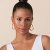 Eine Frau mit dunkelbraunen Haaren und brauner Haut präsentiert das Glossin‘ Glow Tinted Lip Oil 030.