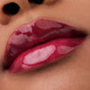 Nahaufnahme der Lippen einer Person mit braunem Haut mit dem Glossin‘ Glow Tinted Lip Oil 020 in glänzendem Pink.