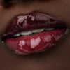 Nahaufnahme der Lippen einer Person mit dunkler Haut mit dem Glossin‘ Glow Tinted Lip Oil 020.