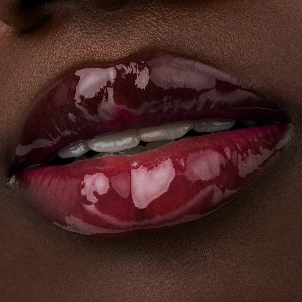 Nahaufnahme der Lippen einer Person mit dunkler Haut mit dem Glossin‘ Glow Tinted Lip Oil 020.