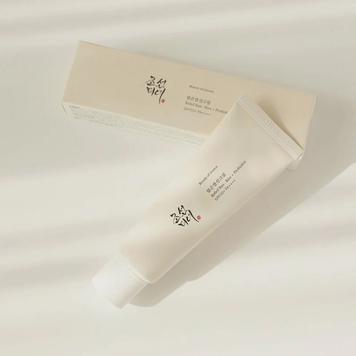 Die Tube und Verpackung des Relief Sun: Rice + Probiotics liegen auf heller Oberfläche und werfen leichte Schatten