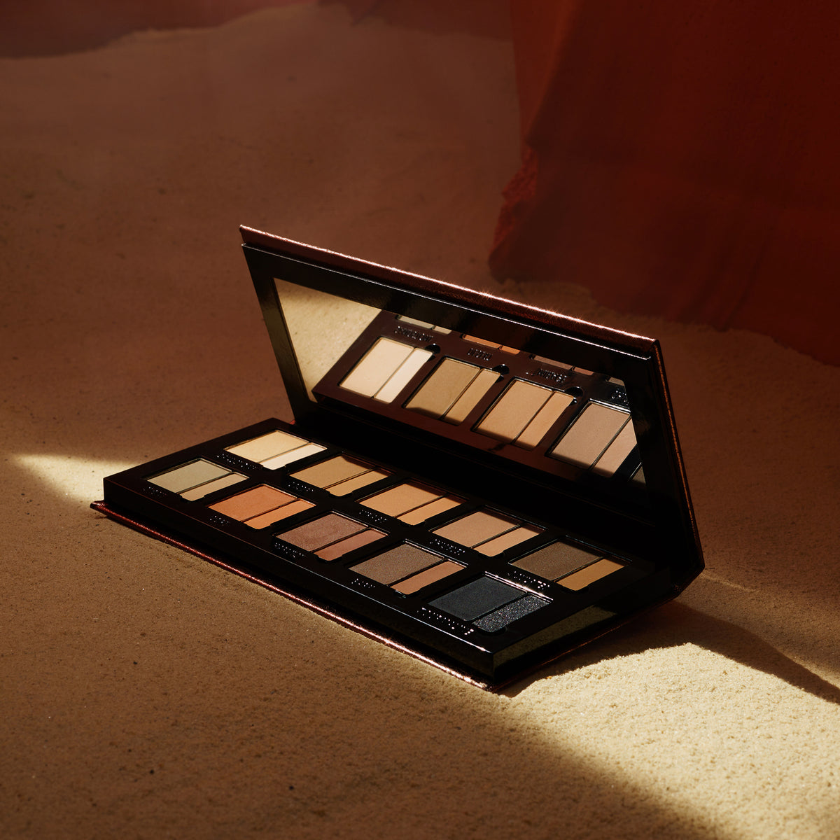 Offene Groundwork Palette – Defining Neutrals ruht auf sandigem Untergrund in sanftem Sonnenlicht.