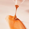 Nahaufnahme der bronze schimmernden DROP OF sunshine BRONZING DROPS auf glatter Oberfläche.