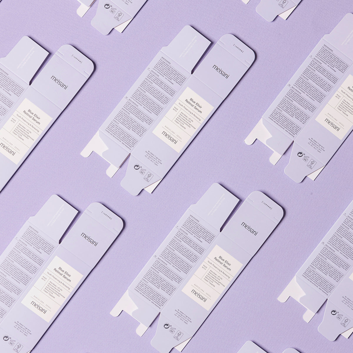 Flache Anordnung mehrerer entfalteter Schachteln des Meisani Blue Elixir Retinol Serums, diagonal auf violettem Hintergrund angeordnet.