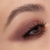 Auge mit weich verblendetem rosé-braunem Lidschatten, der in der Lidfalte intensiviert ist. Die Wimpern sind kräftig getuscht und betont.