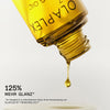 Nahaufnahme einer Flasche N°7 Bonding Oil 30ml, aus dem Haaröl tropft; darunter Text: "125% mehr Glanz."